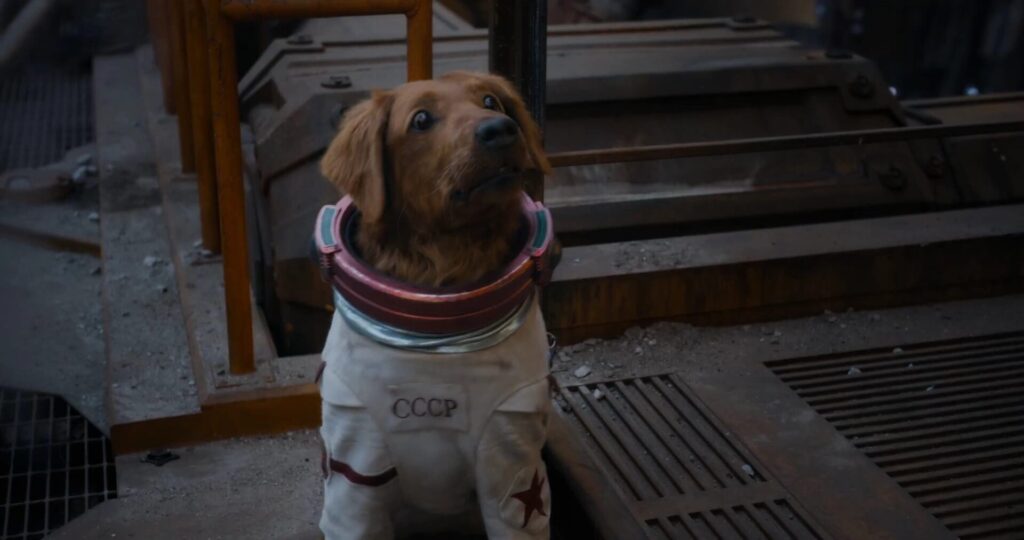 Dog in a white spacesuit with a CCCP patch, looking upward in a gritty, industrial setting.
