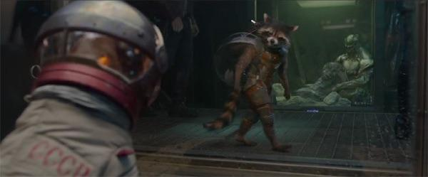 Astronaut in a white suit and helmet watches as a small furry alien sprints through a glass-walled containment chamber.