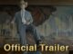 Man in a light gray suit and cowboy hat stands with a cane in front of an industrial factory mural, overlaid with 'Official Trailer' text.