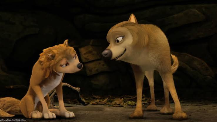 image | GotchaMovies Two wolves share a tender moment in a dark cave, the adult leaning toward the cub.