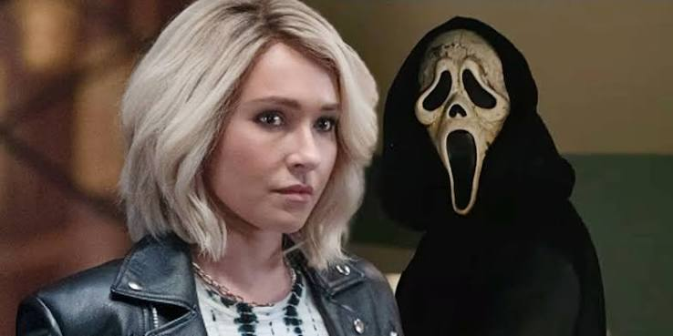 image | GotchaMovies Woman with short blonde hair in a leather jacket standing beside a hooded figure wearing the Ghostface mask from the Scream franchise